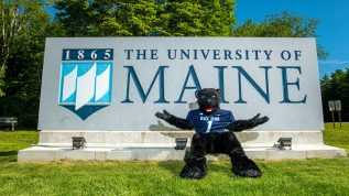 Bananas mascot in front of UMaine sign