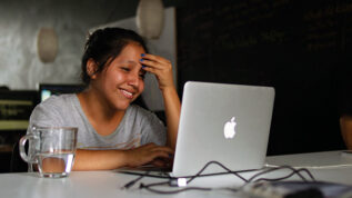Person sitting at laptop smiling with hand on head