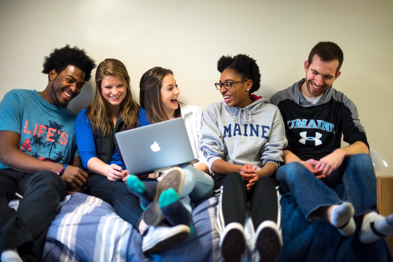 A photo of a group of students sitting around a laptop
