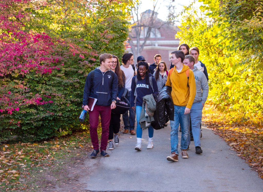 Smiling students walking through UMaine campus