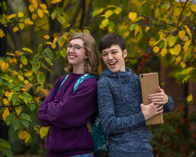 two smiling students with package in fall