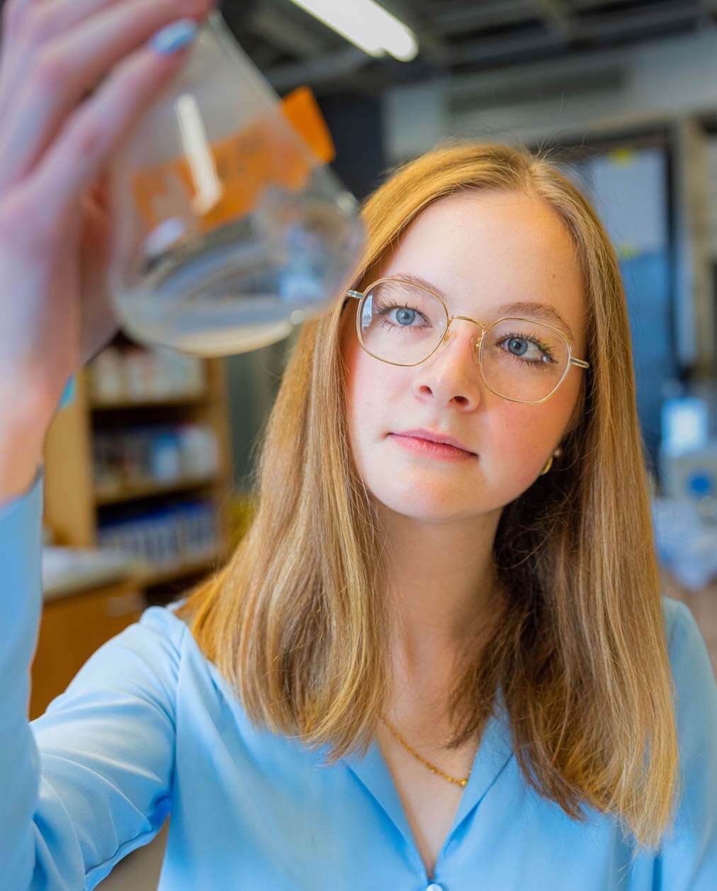 A photo of a person holding a beaker in a lab